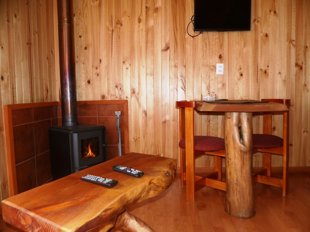 Un interior de madera con chimenea, una mesa y una silla.