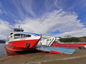 A ferry docked at a pier with a clear sky and mountains in the background. - Cabañas Choshuenco (Panguipulli)