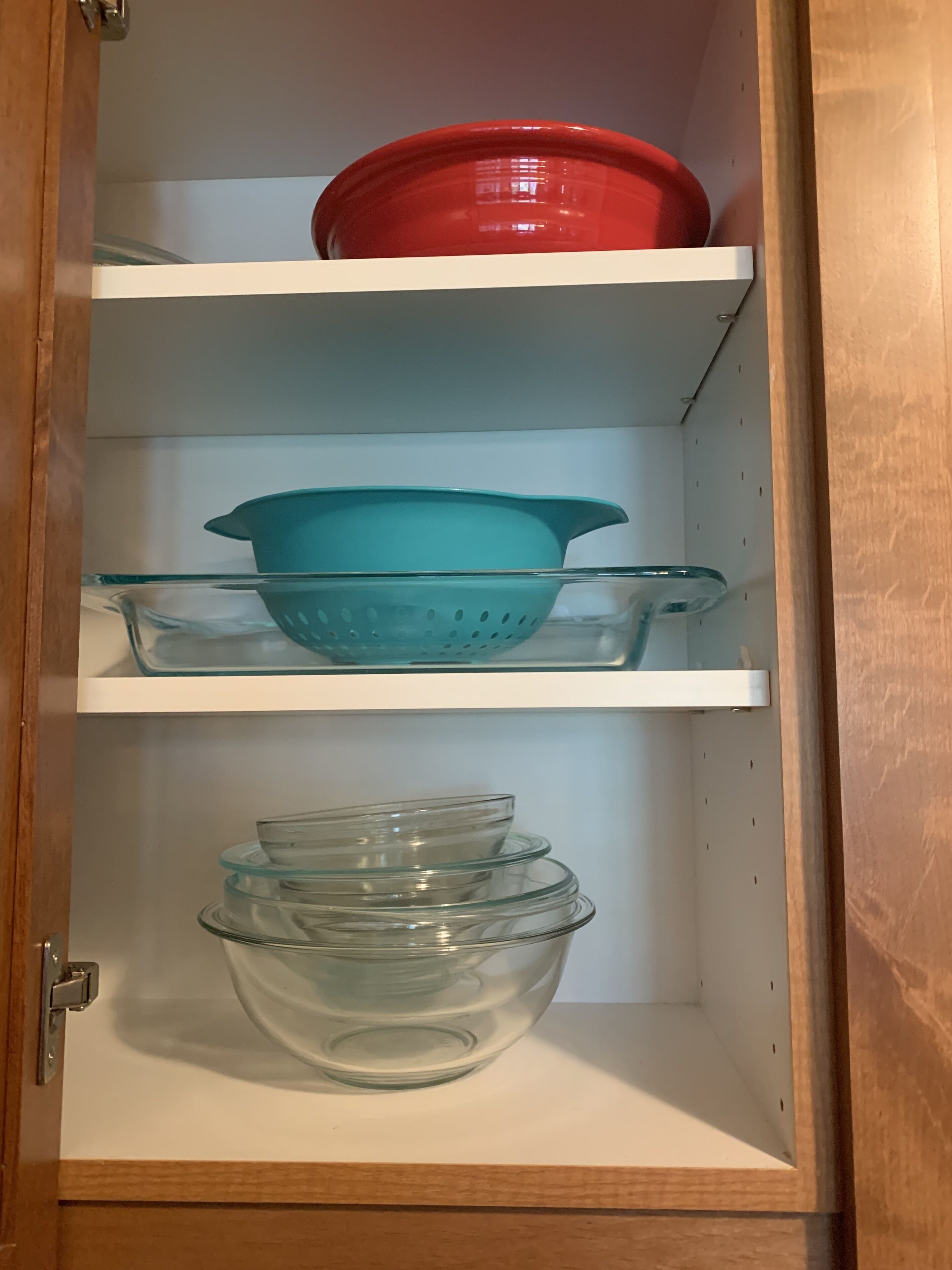 Un mueble de cocina con tres estantes, cada uno con utensilios de cocina diferentes.