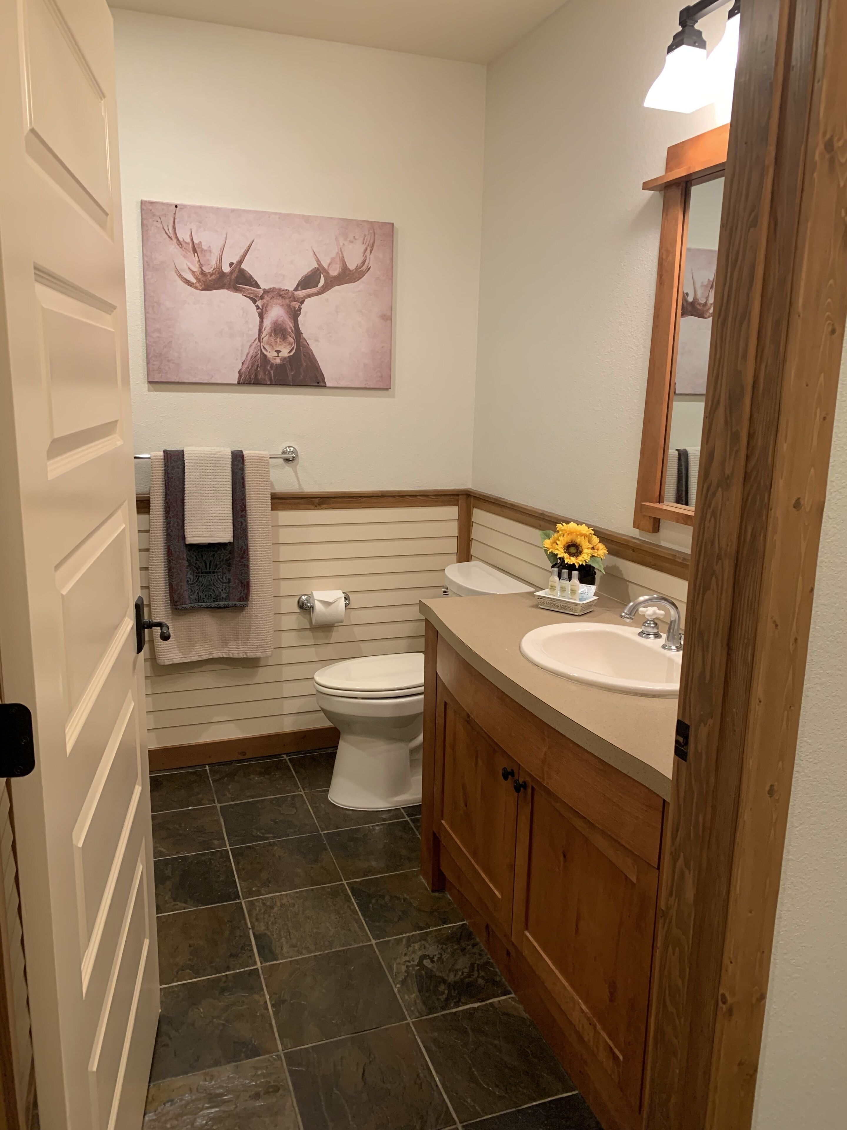 A bathroom with a toilet, sink, and a mirror.