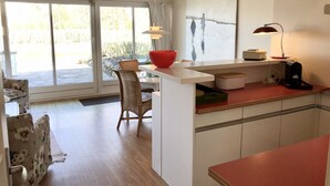 A modern kitchen with a dining area, large windows, and a view of the outdoors. - Cosy, nicely furnished apartment with spacious sunny terrace (Wenningstedt-Braderup (Sylt))
