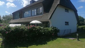 A house with a steeply pitched roof, large windows, and a white exterior. - Cosy, nicely furnished apartment with spacious sunny terrace (Wenningstedt-Braderup (Sylt))