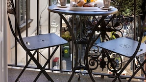 A balcony with two metal chairs, a table with a teapot, cups, and a basket of oranges. - AMORE RENTALS - Maison De Charme with Terraces (Sorrento)