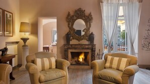 A living room with a fireplace, two armchairs, a lamp, and a mirror. - AMORE RENTALS - Maison De Charme with Terraces (Sorrento)