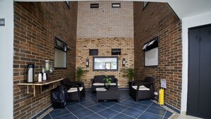 A brick-walled indoor seating area with two sofas and a coffee table, a fire extinguisher, and a small window. - Farum Hotel Medellin (Medellín)