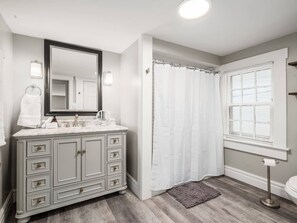 Une salle de bain avec un meuble-lavabo, un miroir et un rideau de douche.
