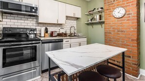 Een moderne keuken met roestvrijstalen apparatuur, een marmeren werkblad en een accentmuur van baksteen.
