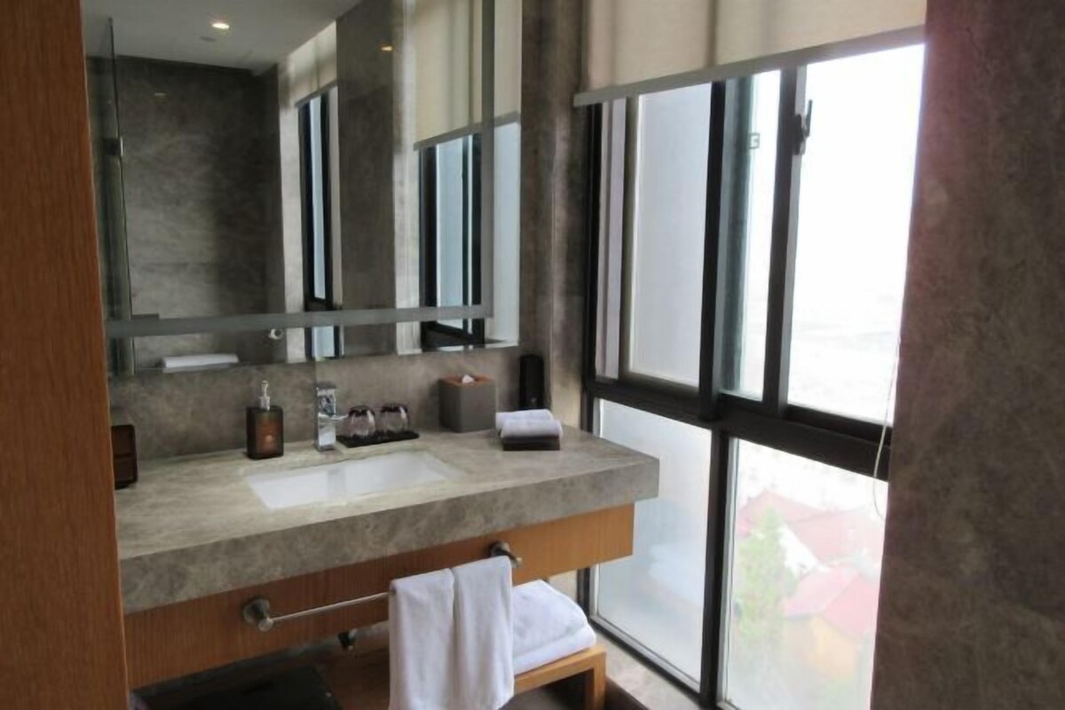 A modern bathroom with a large mirror, a sink, and a window.