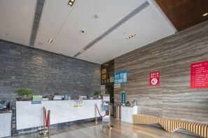 A reception area with a marble wall, a reception desk, and a seating area. - Qingyang Tongtaiyuan Grand Hotel (Qingyang District) (Qingyang)