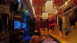 Un intérieur luxueux avec un sol en marbre, un long canapé et un écran de télévision.