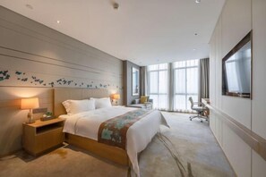 A hotel room with a large bed, bedside tables, a desk, and a TV.