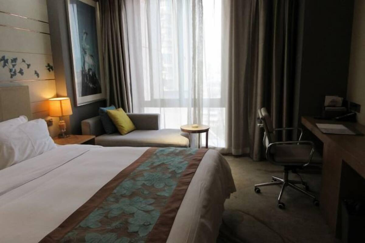 Quarto de hotel com uma cama grande, um sofá, uma escrivaninha e uma cadeira.