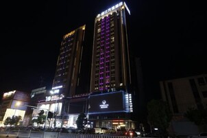Un hotel moderno de gran altura con señalización iluminada y una entrada destacada.