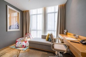 A hotel room with a bed, a desk, a chair, a window with curtains, and a framed picture on the wall. - Qingyang Tongtaiyuan Grand Hotel (Qingyang District) (Qingyang)