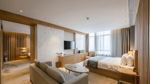 Une chambre d’hôtel moderne équipée d’un canapé, d’un lit, d’une télévision et d’un bureau.