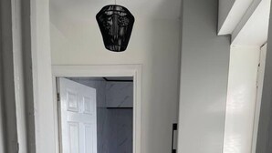 Un couloir aux murs blancs et au sol en marbre, qui mène à une pièce dont la porte est également blanche.