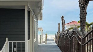 Un chemin menant à une maison de plage, avec une pancarte indiquant qu’il s’agit d’une propriété privée, une entrée fermée par un portail et une vue sur l’océan.