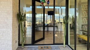 Une entrée moderne avec des portes vitrées, un cactus, un paillasson et une vue sur l’intérieur.