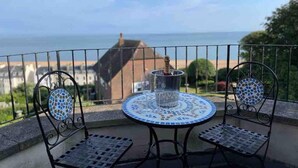 A balcony with a round table and two chairs, overlooking a scenic view of the sea and buildings. - The Turret - The Best View in Folkestone (Folkestone)