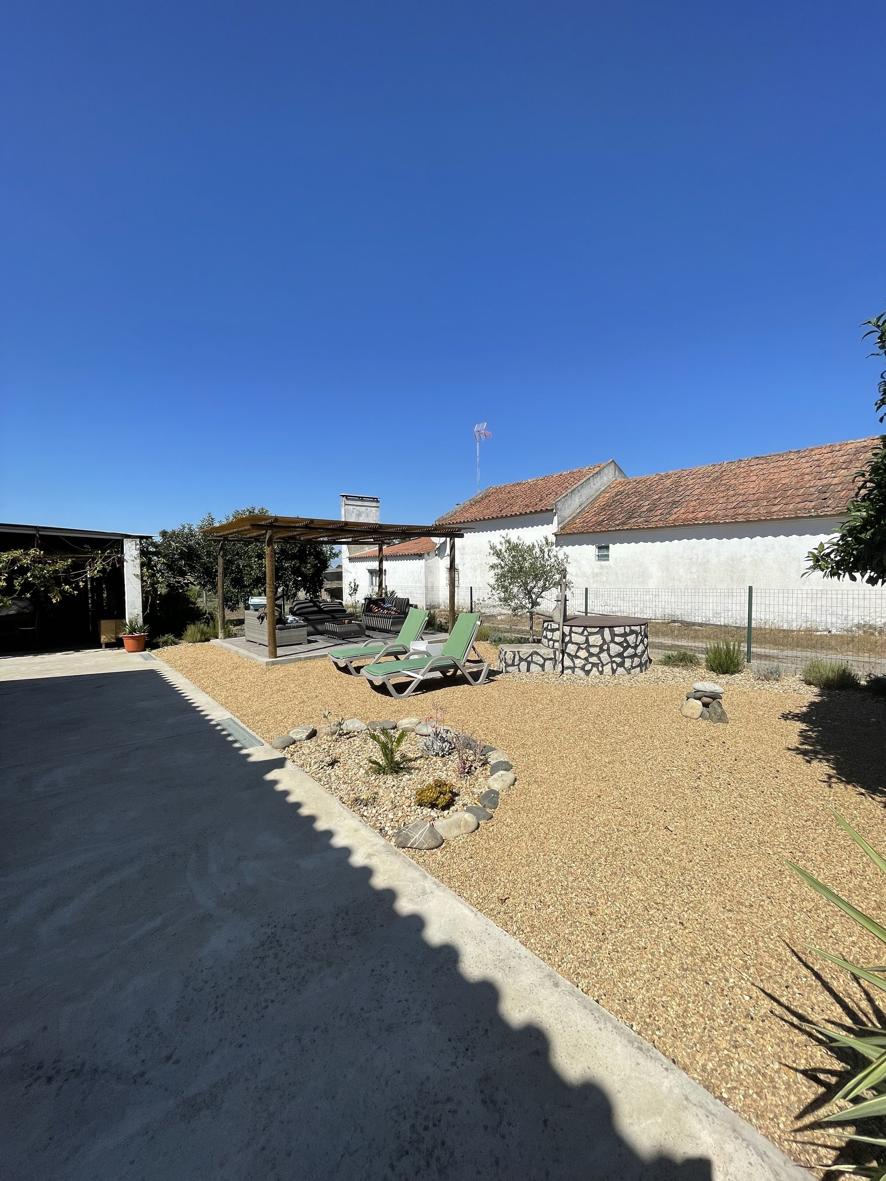 A patio area with outdoor seating, a pergola, and a garden bed with rocks and plants.