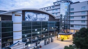 A modern hotel with a curved facade, large windows, and a central courtyard. - Xinhong Hotel (Weiyuan)