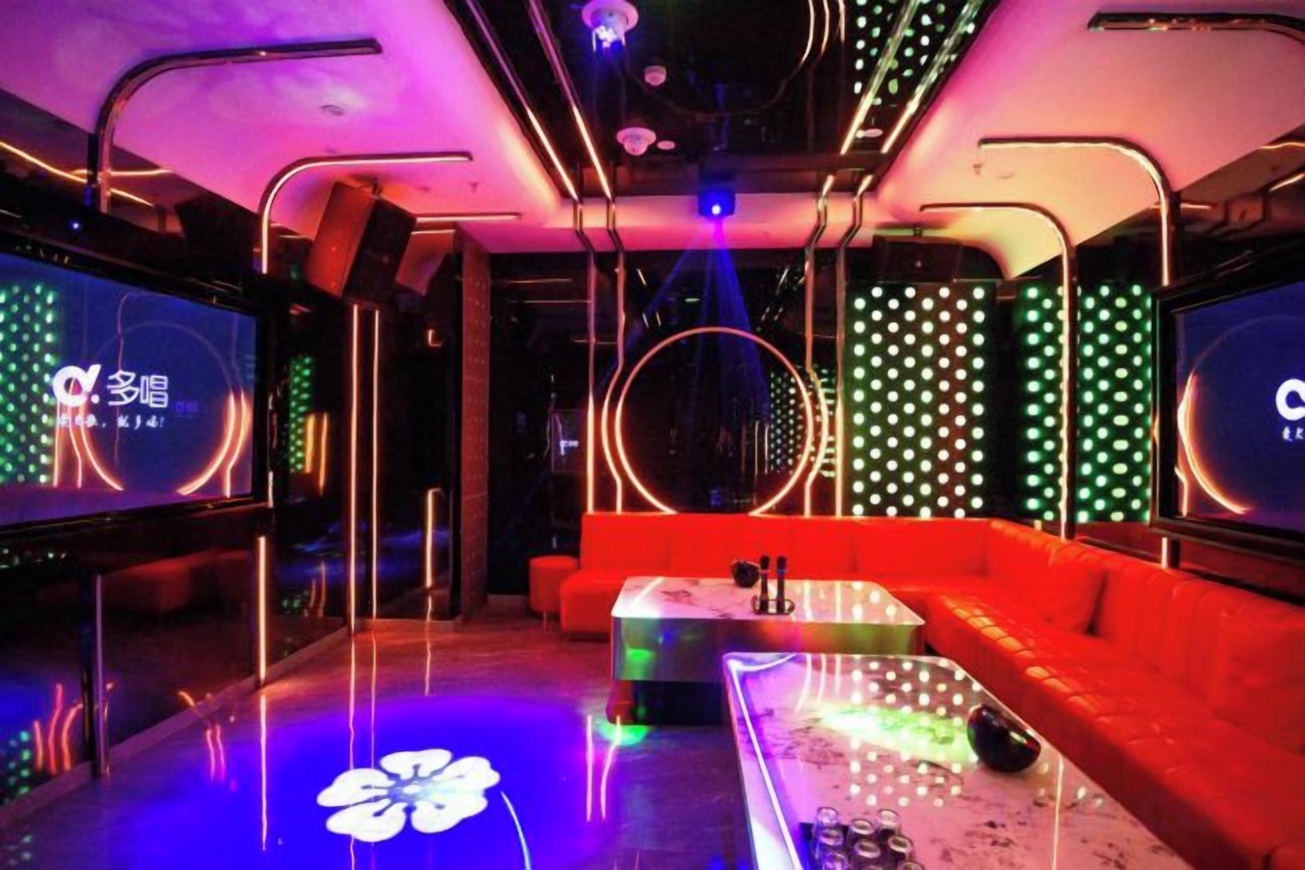 A modern interior with a bar area, seating, and entertainment screens.