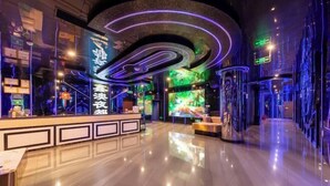 A modern hotel lobby with a reception desk, a large digital screen, and a sleek, curved ceiling design. - Xinhong Hotel (Weiyuan)