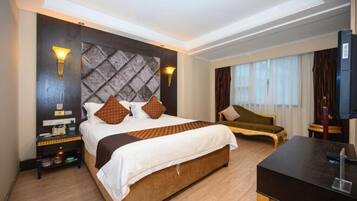 Habitación de hotel con una cama grande, un escritorio, una silla y un televisor.
