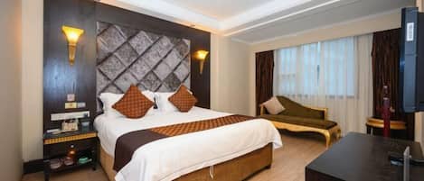 Habitación de hotel con una cama grande, un escritorio, una silla y un televisor.