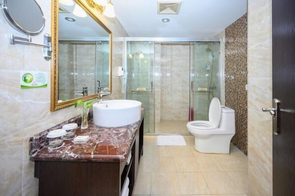 A modern bathroom with a marble vanity, a large mirror, a glass shower enclosure, and a toilet. - Xinhong Hotel (Weiyuan)