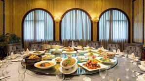 A round dining table with various dishes and glasses, set in a room with arched windows and plush seating. - Xinhong Hotel (Weiyuan)