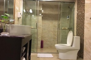 A modern bathroom with a glass-enclosed shower, a white toilet, and a marble-tiled vanity. - Xinhong Hotel (Weiyuan)