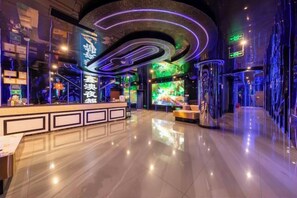 A hotel lobby with a reception desk, a large digital screen, and a modern, curved ceiling design. - Xinhong Hotel (Weiyuan)