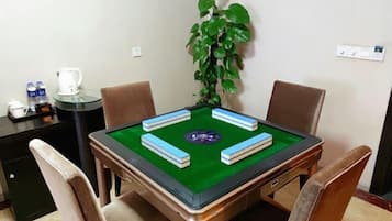 A room with a pool table, four chairs, a coffee maker, water bottles, and a potted plant.