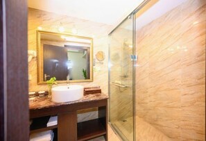 A bathroom with a marble sink, a large mirror, and a glass shower enclosure. - Xinhong Hotel (Weiyuan)
