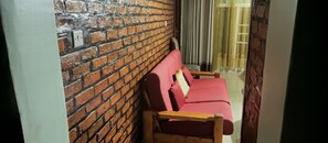 A room with a brick wall, a wooden bench, and a red sofa.