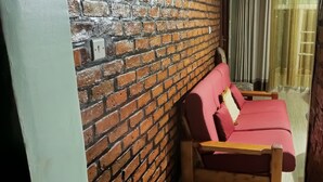 A room with a brick wall, a wooden bench, and a red sofa. - Charming 2-bed House in Kigali (Kigali)