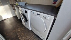 A compact laundry area with a washing machine, a drying machine, and a countertop with a sink and dish rack. - Tall Pines Lodge Dog Friendly, Nr Sutton on Sea (Mablethorpe)