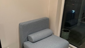 Un sofá gris con reposapiés en una esquina de una habitación con un ventanal grande.