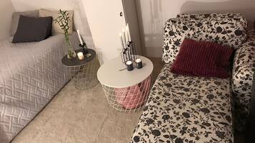 A cozy living room with a patterned sofa, a round coffee table, and a small side table with candles.