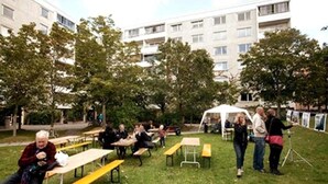 An outdoor seating area with tables and benches, surrounded by trees and a building in the background. - Casa South Studio in the Center of Stockholms Soho (Stockholm)
