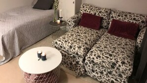 A small, cozy room with a bed, a sofa, and a round table with candles. - Casa South Studio in the Center of Stockholms Soho (Stockholm)