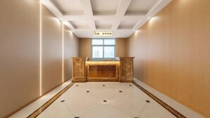 Un hall d’hôtel avec un comptoir d’accueil, une grande fenêtre et un sol carrelé.