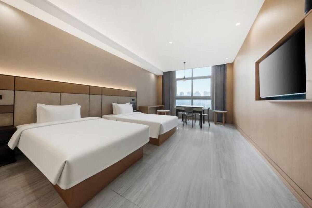Een hotelkamer met twee bedden, een bureau en een televisie.