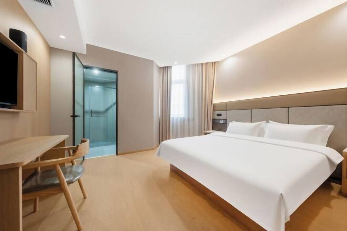 Een hotelkamer met een bed, een bureau, een stoel, een televisie en een deur naar een badkamer.