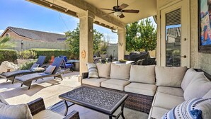An outdoor patio area with a covered seating area, including a sofa and lounge chairs, a table, and a ceiling fan. - Pool, BBQ & Fire Pit: Family Home in Cave Creek (Cave Creek)