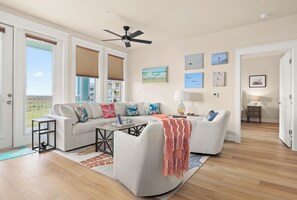 A living room with a sofa, armchairs, a coffee table, and a ceiling fan.