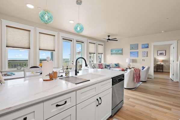 A modern kitchen with a large island, white cabinetry, and a ceiling fan.