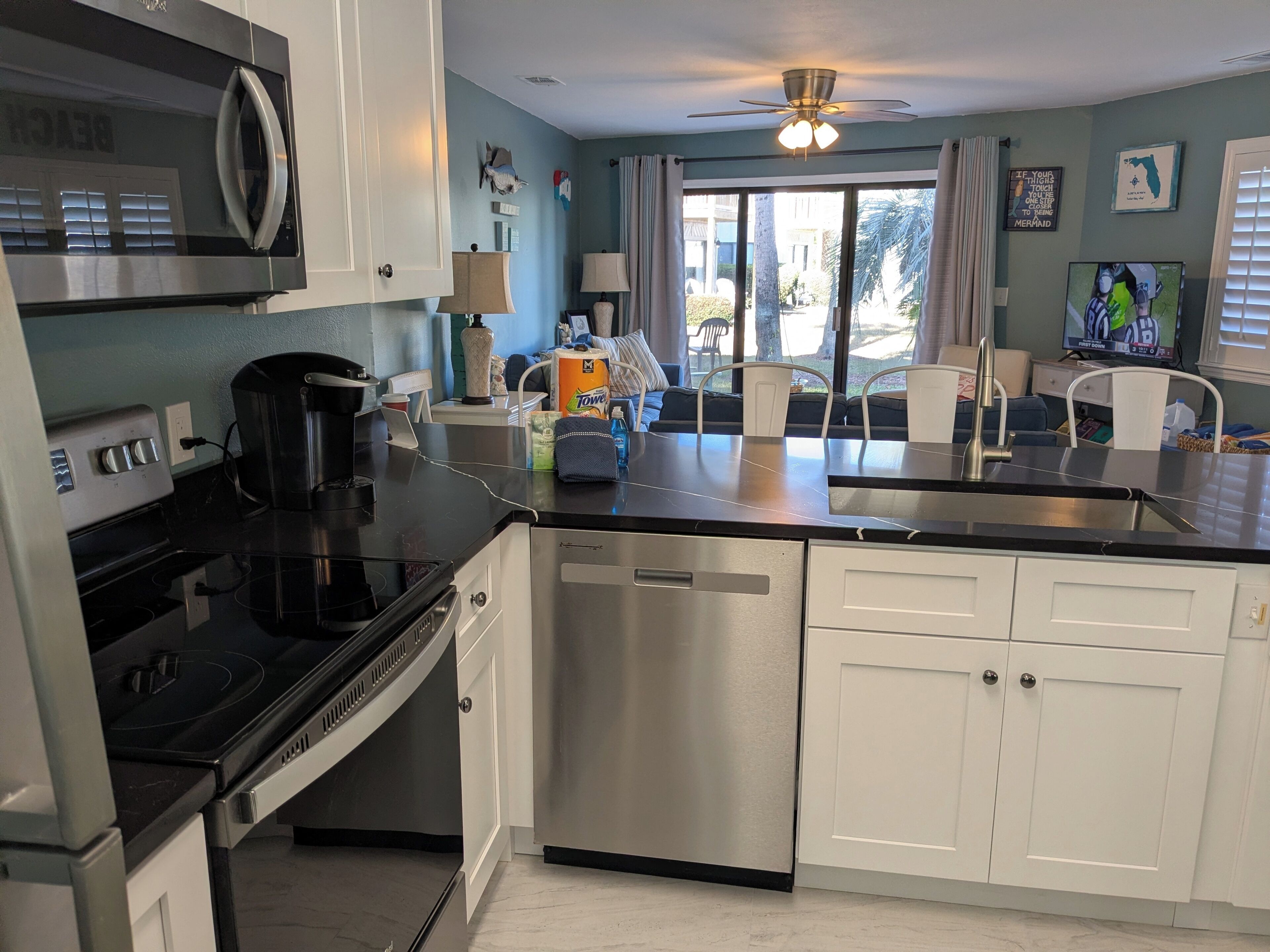 A modern kitchen with stainless steel appliances, a dishwasher, and a dining area with a view to the outdoors.