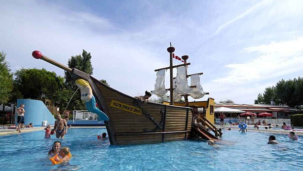 A swimming pool with a pirate ship play structure.